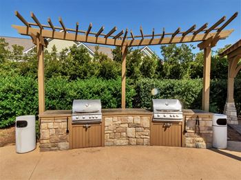 Outdoor kitchen with dual grills under wooden pergola