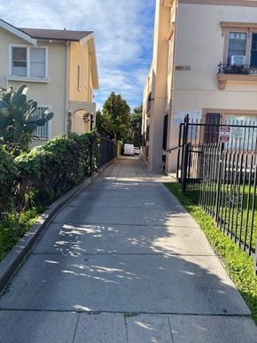 Los Angeles apartment for rent - A sidewalk runs down a quiet street between two buildings.