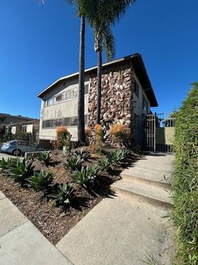 Los Angeles apartment for rent - A house with a stone wall and a palm tree in front.