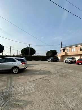 Los Angeles apartment for rent - A silver car is parked in a lot with other cars and a house in the background.