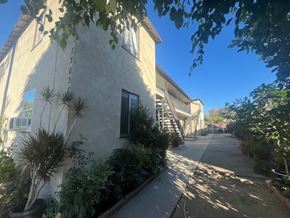 Van Nuys apartment for rent - A sunny day in a quiet residential street with a house on the left and a tree in the foreground.