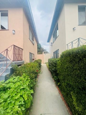 Valley Village apartment for rent - A narrow pathway between two buildings with green shrubbery on the sides.