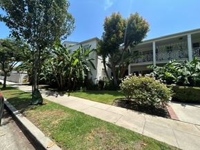 Los Angeles apartment for rent - A white building with a balcony is surrounded by greenery.