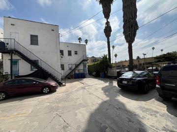 Los Angeles apartment for rent - A parking lot with cars and a building with a staircase.