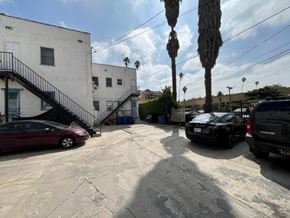 Los Angeles apartment for rent - A parking lot with cars and a building with a staircase.