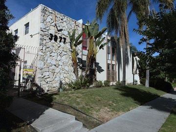 Los Angeles apartment for rent - A white building with a stone wall on the side.