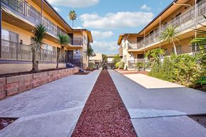 Los Angeles apartment for rent - A long, narrow walkway with a red brick border separates two rows of apartment buildings.