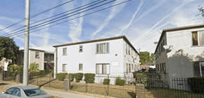 Van Nuys apartment for rent - A white house with a grey roof is surrounded by a black fence.