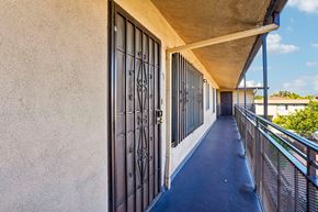Los Angeles apartment for rent - A long, narrow walkway with a metal railing and a closed gate.