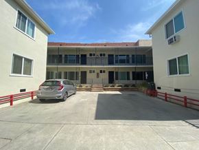 Los Angeles apartment for rent - A car is parked in a parking lot in front of a building.