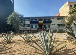 Los Angeles apartment for rent - A building with a yellow sign on the front and a black fence in front of it.