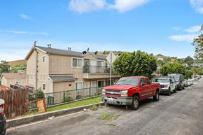 Los Angeles apartment for rent - A red pickup truck is parked on the side of a street lined with houses and parked cars.
