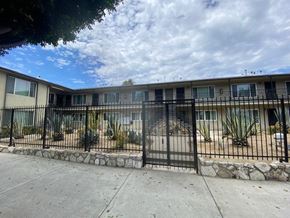 Los Angeles apartment for rent - A black metal fence surrounds a building with a stone base.