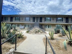 Los Angeles apartment for rent - A concrete walkway leads to a building with a staircase in front.