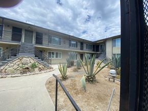 Los Angeles apartment for rent - A view of a courtyard with a fence, plants, and a building in the background.