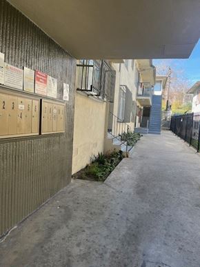Los Angeles apartment for rent - A long concrete walkway leads to a building with a row of mailboxes on the left.