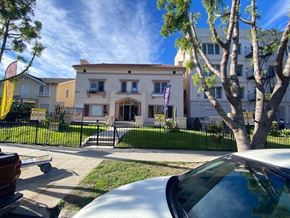 Los Angeles apartment for rent - A white car is parked in front of a building with a black fence.