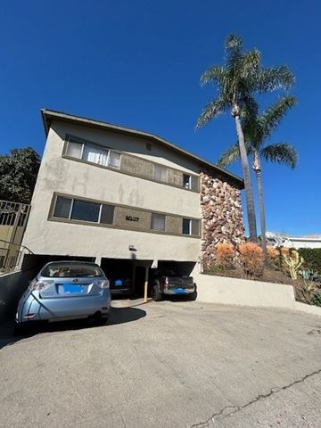 Los Angeles apartment for rent - A car is parked in front of a building with a palm tree in the background.