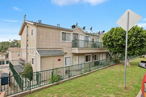 Los Angeles apartment for rent - A building with a green fence and a sign in front of it.