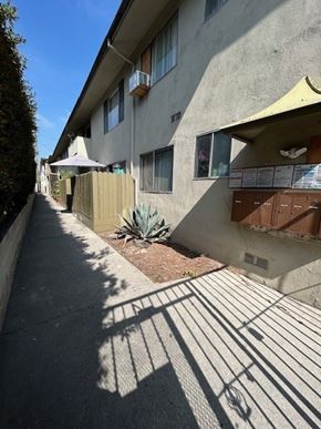 Los Angeles apartment for rent - A sunny day in a residential area with apartment buildings and a sidewalk.