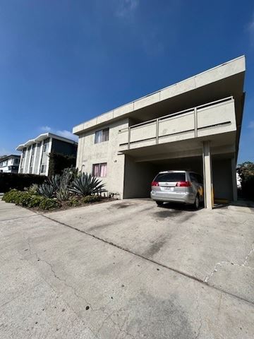 Los Angeles apartment for rent - A silver car is parked in a garage door of a building.