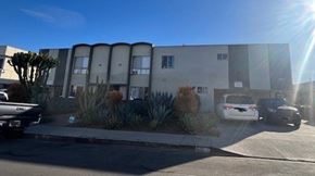 Los Angeles apartment for rent - A white car is parked in front of a grey building.
