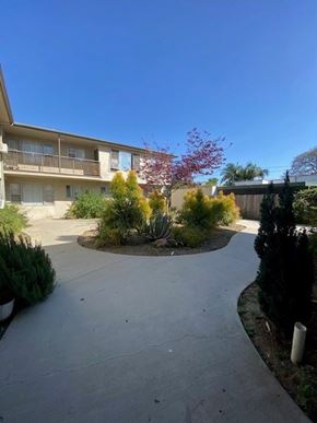 Los Angeles apartment for rent - A concrete pathway leads to a two-story apartment building with a balcony.