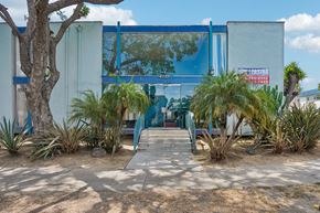 Los Angeles apartment for rent - A blue building with a glass window and a red sign on it.