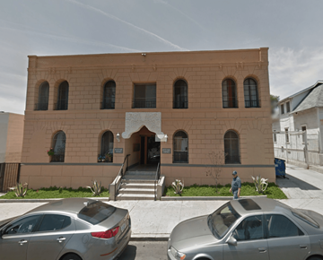 Los Angeles apartment for rent - A tan building with a man standing in front of it.
