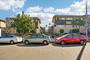 Los Angeles apartment for rent - Three cars parked in a lot with a building in the background.
