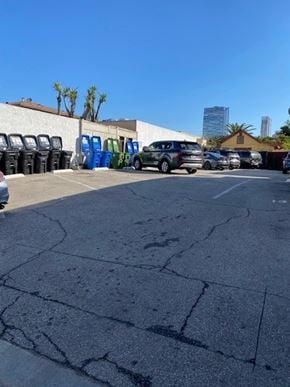 Los Angeles apartment for rent - A parking lot with a white car and a blue car parked in front of a building.