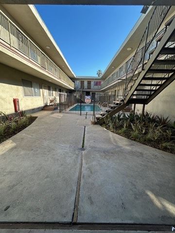 Los Angeles apartment for rent - A concrete walkway leads to a pool area in a residential complex.