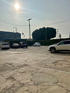 Los Angeles apartment for rent - A parking lot with a white car in the foreground and a building in the background.