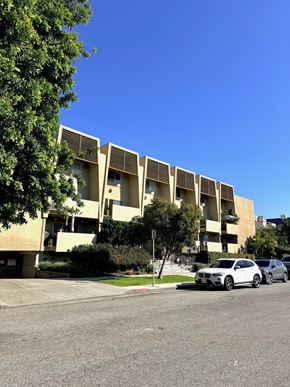 Santa Monica apartment for rent - A white car is parked in front of a building with a tree to the left.