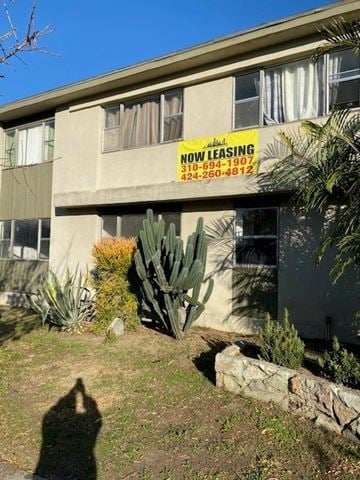 Los Angeles apartment for rent - A building with a sign that says "Now Leasing" is surrounded by plants and trees.