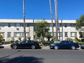 Los Angeles apartment for rent - Two cars parked in front of a building with a sign that says "Now Legging".
