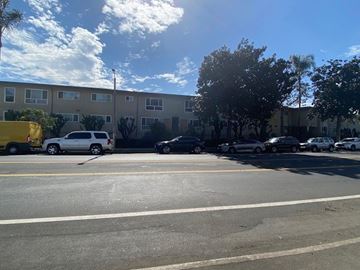 Los Angeles apartment for rent - A parking lot with cars and a yellow truck in front of a building.