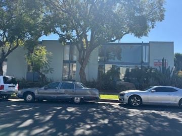 Los Angeles apartment for rent - Two cars parked in front of a building with trees in the background.