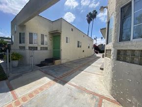 Los Angeles apartment for rent - A white house with a green door and a red brick walkway.