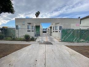 Los Angeles apartment for rent - A concrete pathway leads to a building with a green fence on either side.