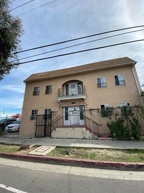 Los Angeles apartment for rent - A beige house with a black gate and a red brick sidewalk.