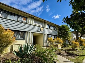 Los Angeles apartment for rent - A grey building with a yellow signboard in front of it.