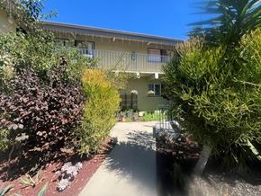 Los Angeles apartment for rent - A building with a balcony is surrounded by green plants.