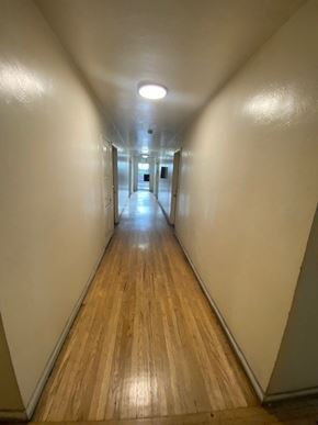 Maywood apartment for rent - A long hallway with wooden floors and white walls.