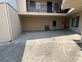 Los Angeles apartment for rent - A balcony with a railing and chairs is on the second floor of a building.