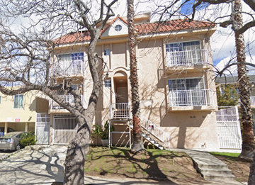 Los Angeles apartment for rent - A beige two-story building with a red tile roof and a balcony on the second floor.
