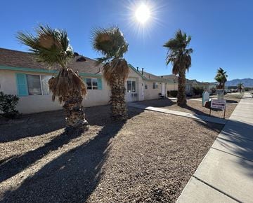 Fort Mohave apartment for rent - A sunny day with palm trees and houses in the background.