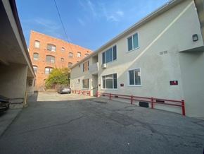 Los Angeles apartment for rent - A parking lot in front of a building with a red fence.