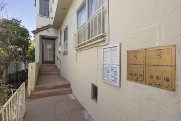 Los Angeles apartment for rent - A white building with a brown door and a sign on the wall.