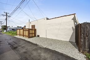 Los Angeles triplex for rent - A white building with a brown door and a wooden fence.